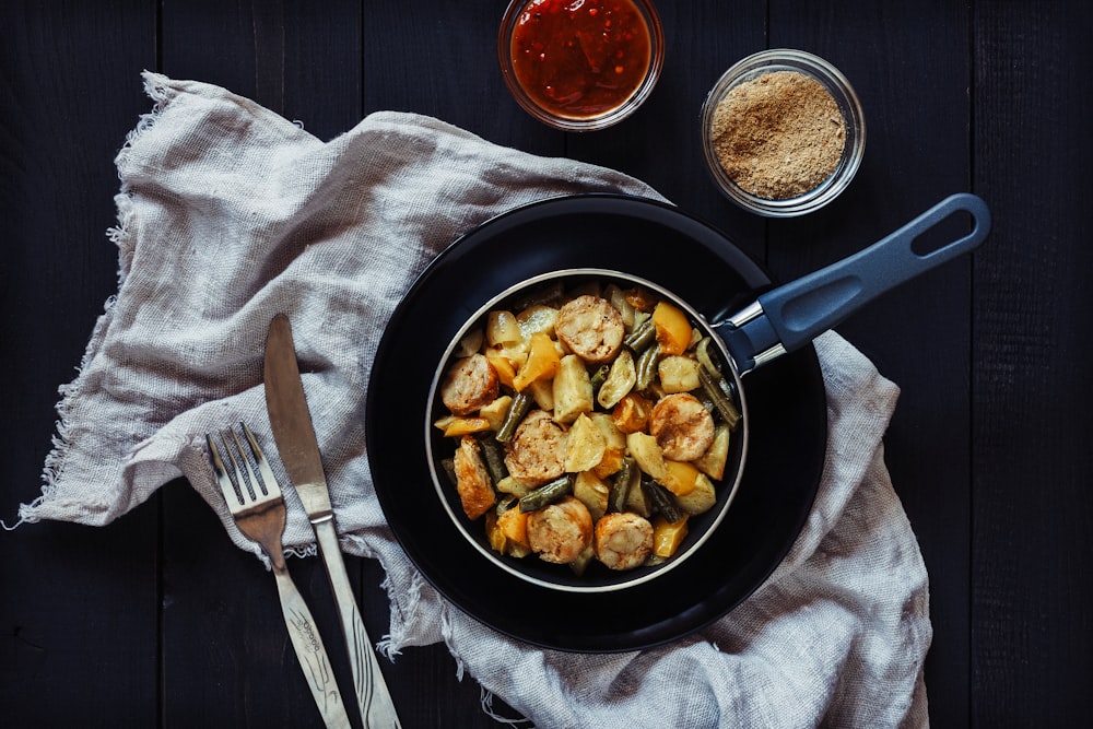 a pan filled with food next to a fork and knife