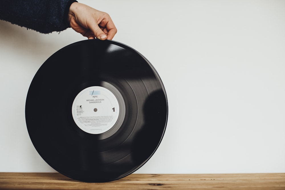 a person holding a record on top of a wooden table