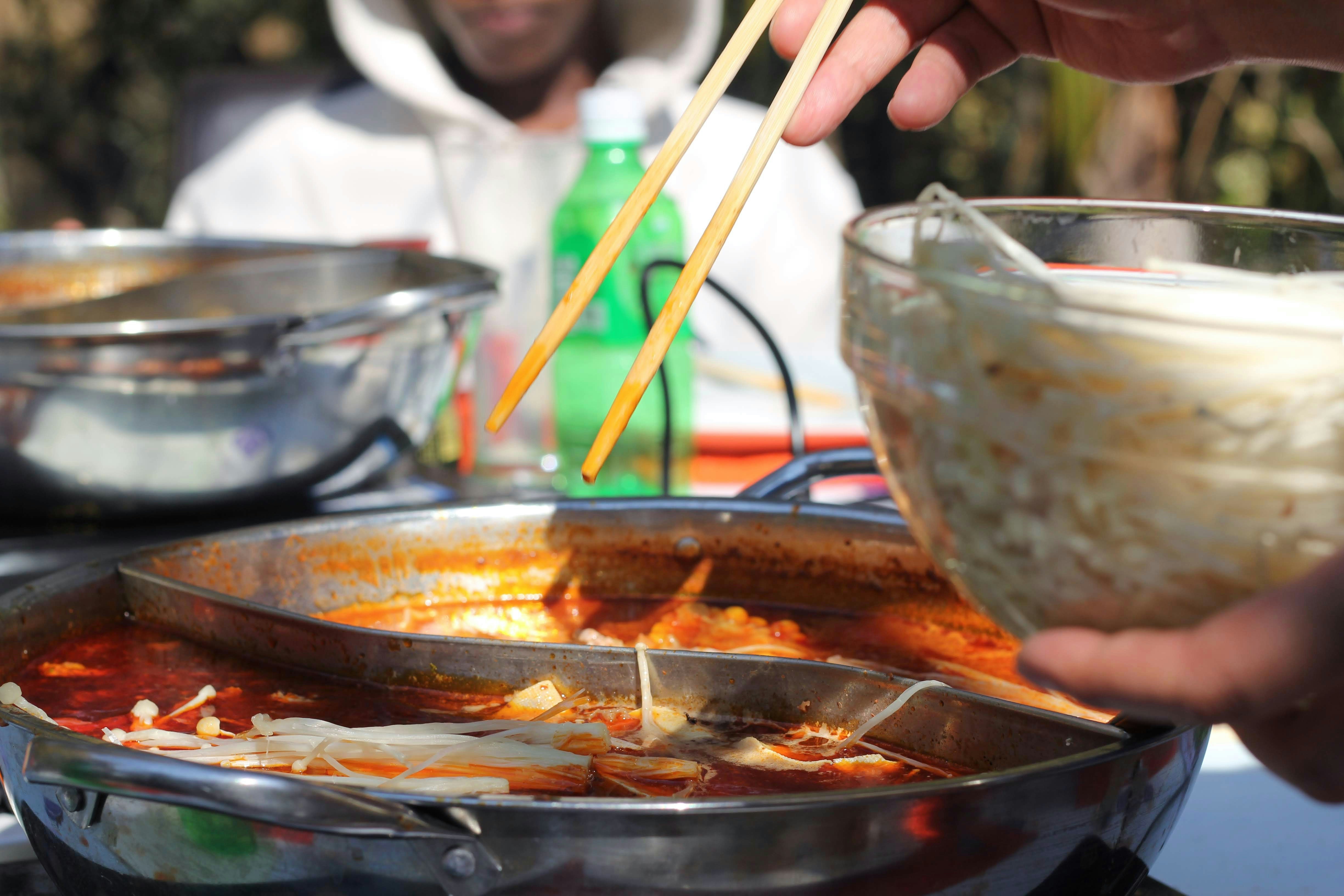 a person holding chopsticks over a bowl of food