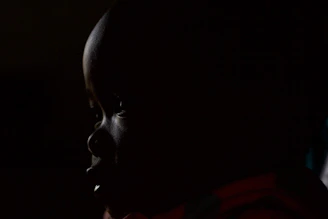 An artistic photo of a person silhouetted against a dimly lit background, emphasizing shadows and contrast