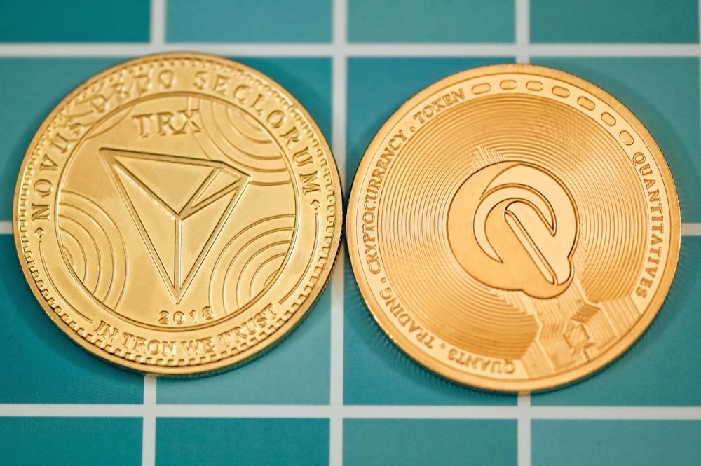 a close up of two gold coin on a tiled surface