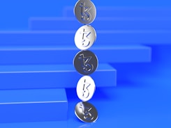 A vertical stack of silver coins with a stylized 'tz' symbol, set against a blue background with geometric, stair-like shapes.