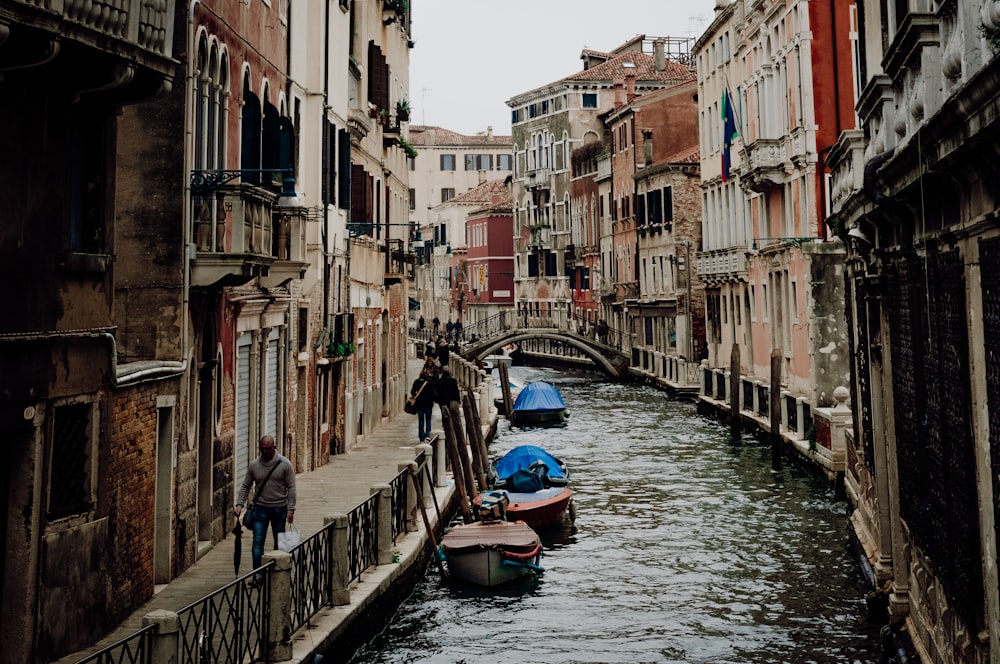 a couple of boats floating down a river next to tall buildings