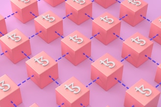 A pattern of pink cubes connected by blue dotted lines. Each cube displays a stylized white letter resembling an abstract symbol. The background is a lighter shade of pink, creating a monochromatic appearance.