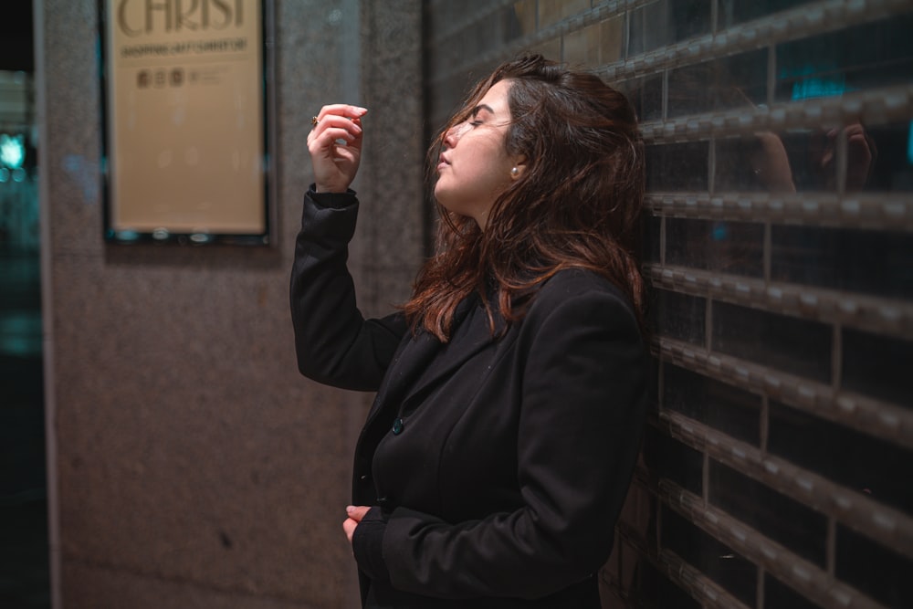 a woman standing next to a wall with a sign on it