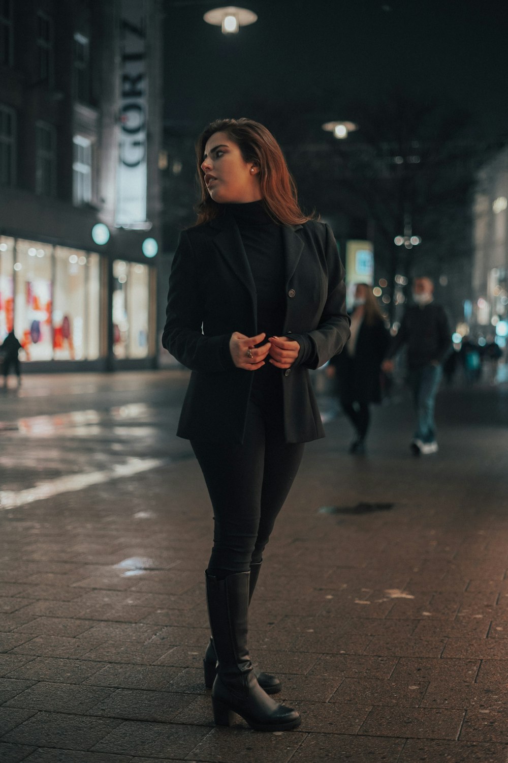 a woman standing on a sidewalk at night