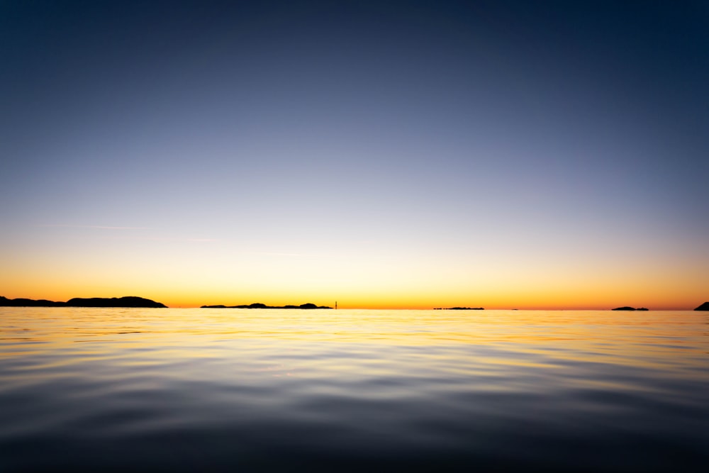 a body of water with a sunset in the background