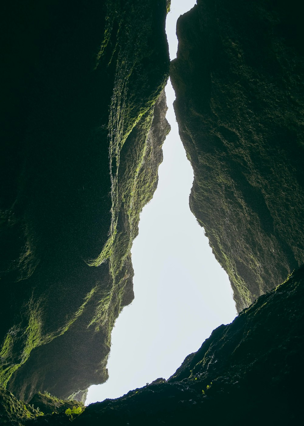 a person standing in a cave looking up at the sky