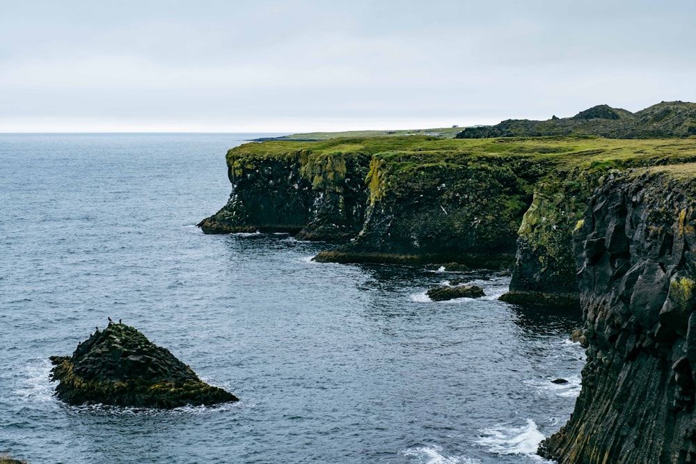 a large body of water next to a rocky cliff