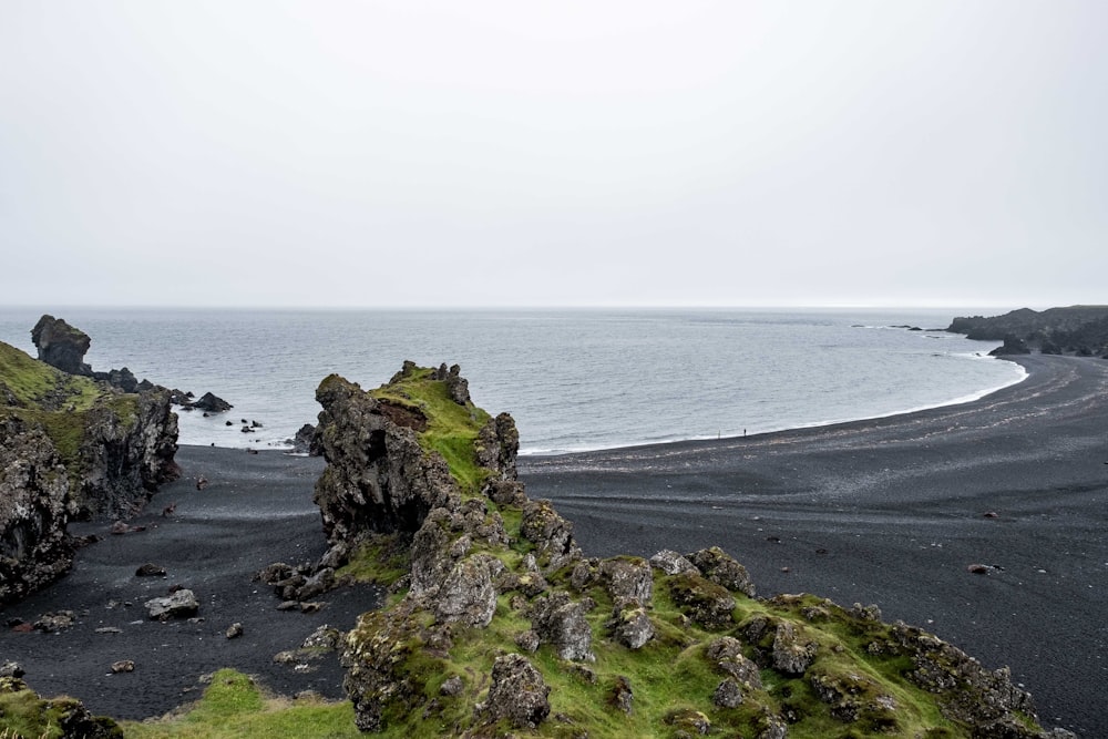 Una playa de arena negra junto a un cuerpo de agua