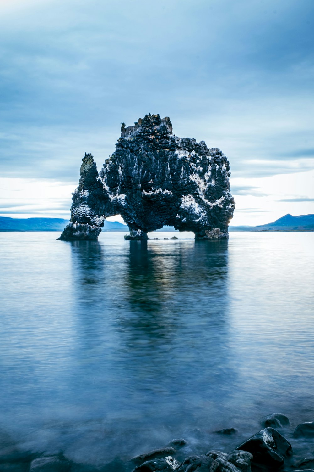 une grande formation rocheuse au milieu d’un plan d’eau