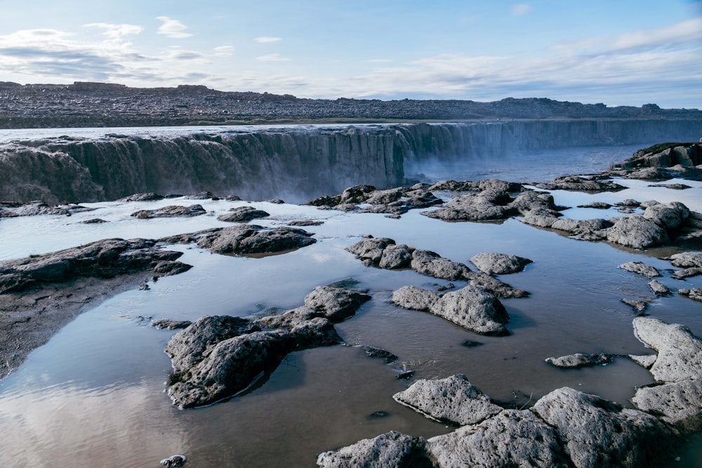 a large waterfall with a body of water near it