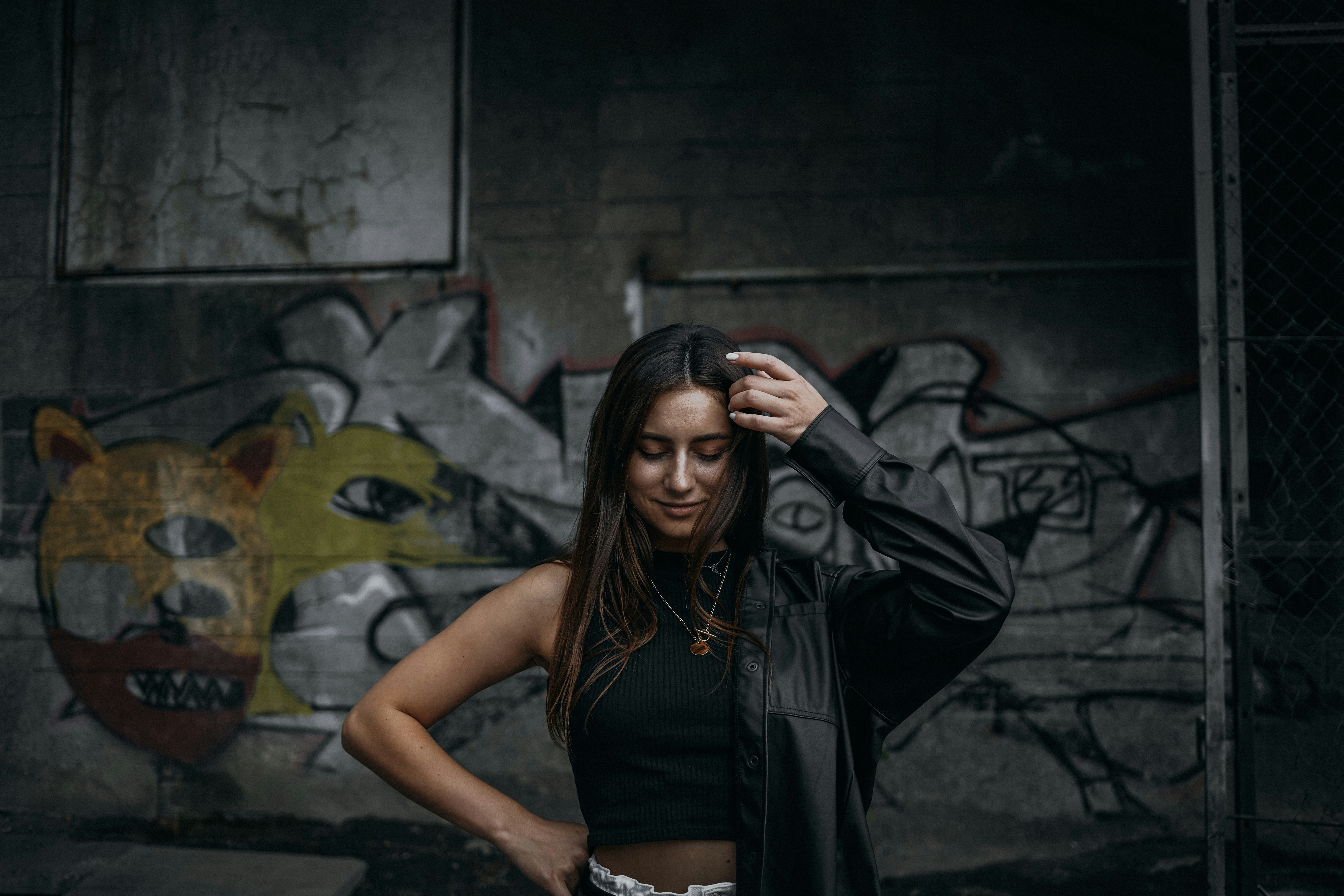 a woman standing in front of a graffiti covered wall