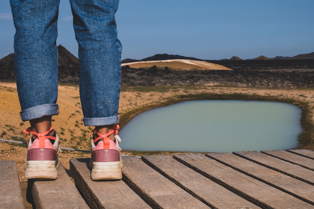 a person standing on a wooden platform next to a body of water