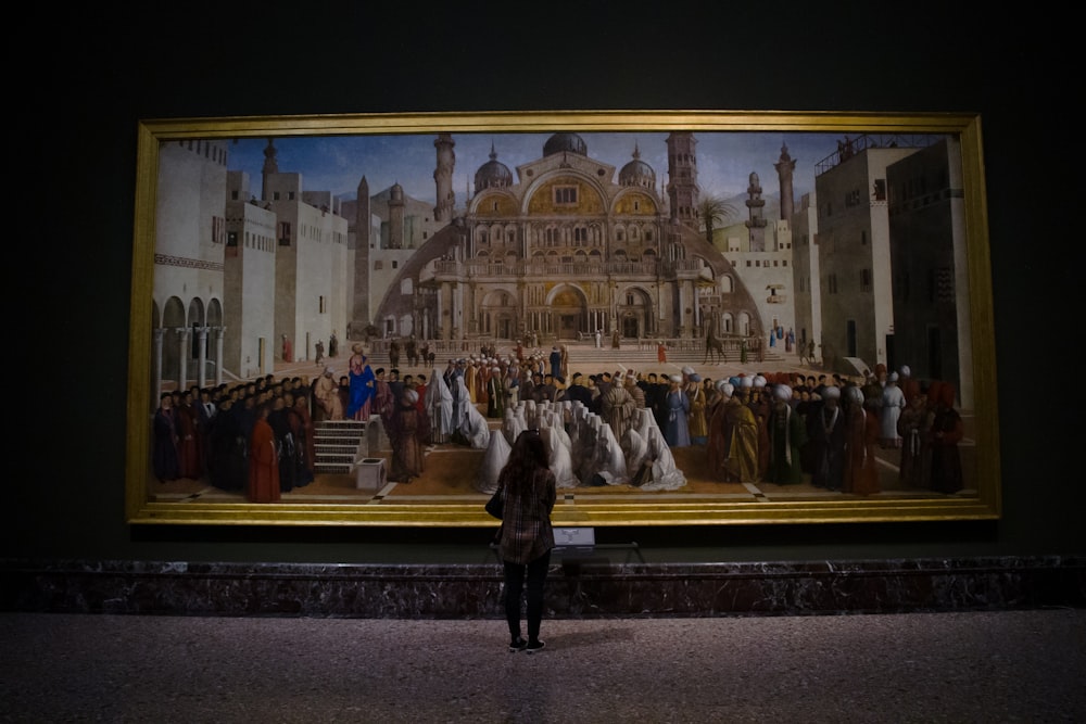 Una mujer parada frente a una gran pintura