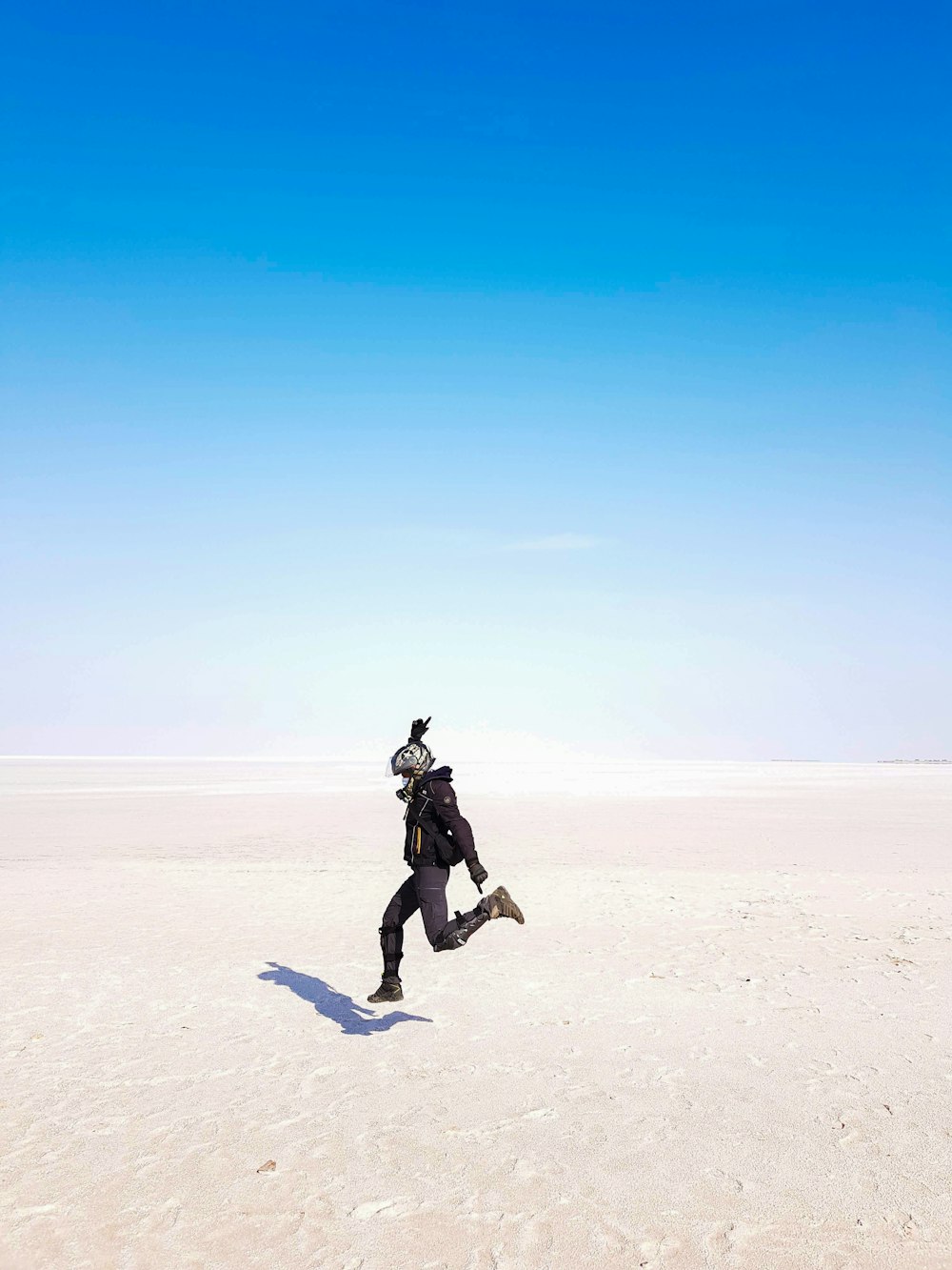 a man running across a sandy plain under a blue sky