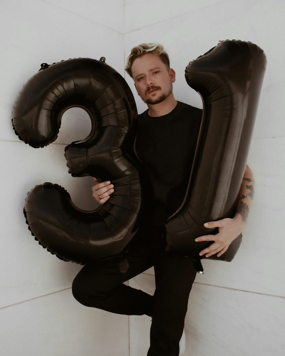 a man holding a large balloon in the shape of the number 3