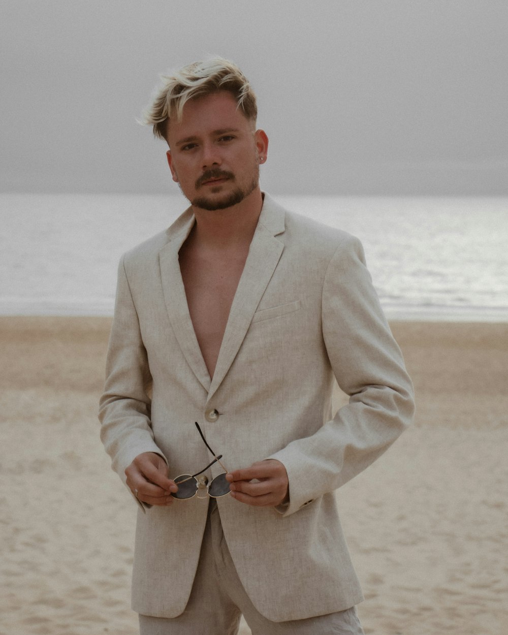 a man standing on a beach holding a pair of scissors