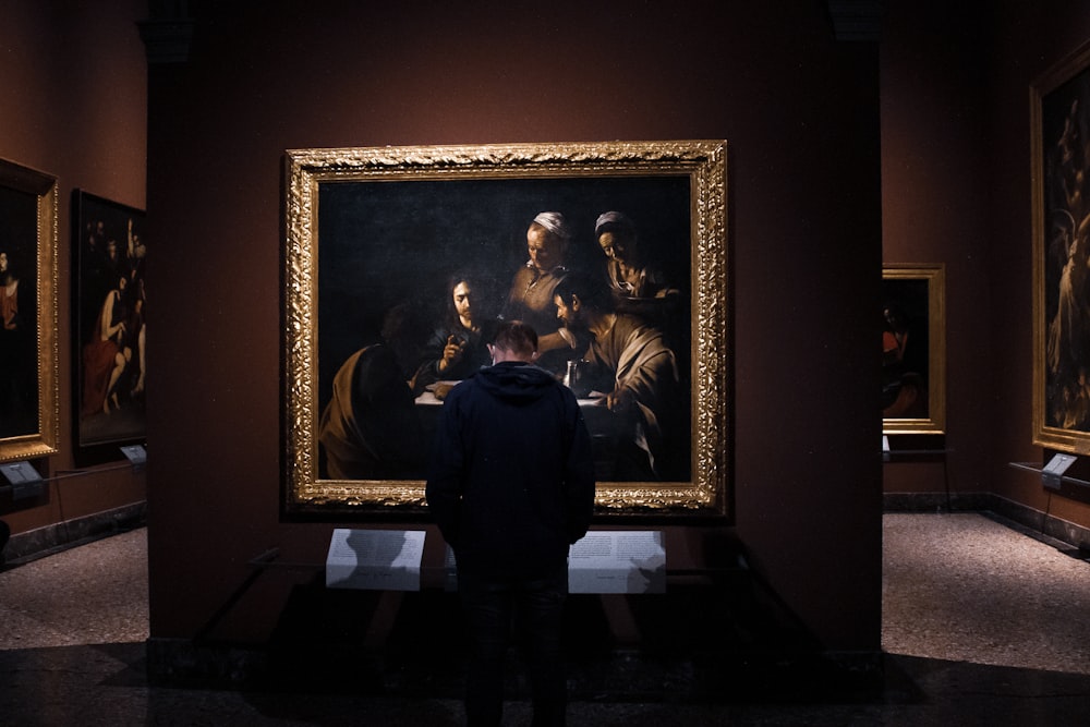 um homem em pé na frente de uma pintura em um museu