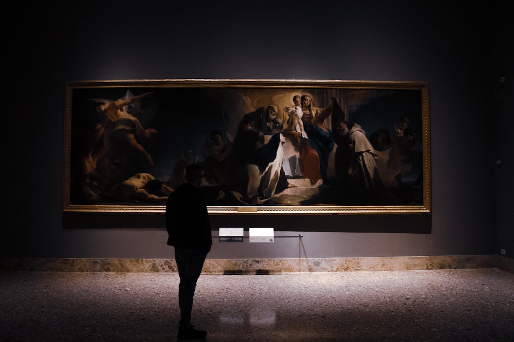 Una persona parada frente a una pintura grande