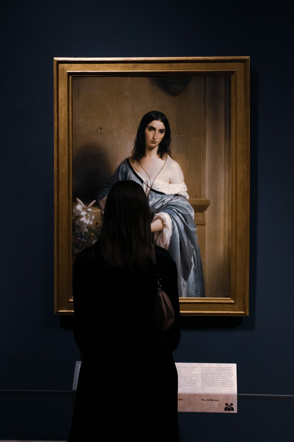 a woman standing in front of a painting of a woman