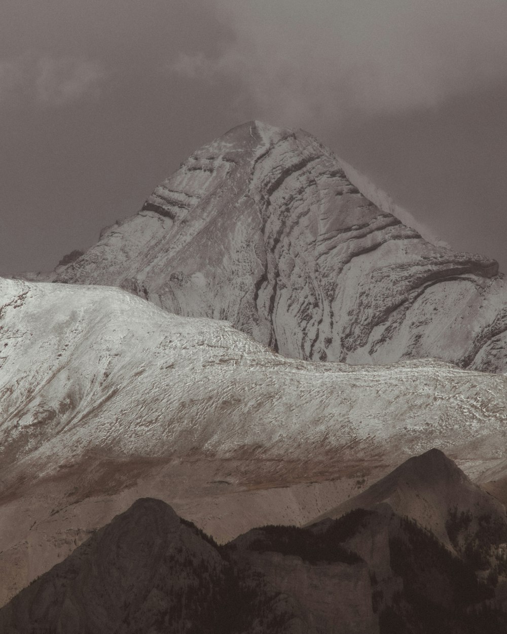 a mountain covered in snow under a cloudy sky