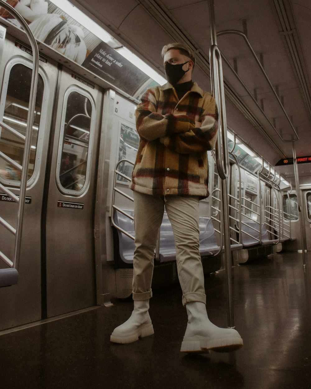 a man standing on a subway train with his arms crossed