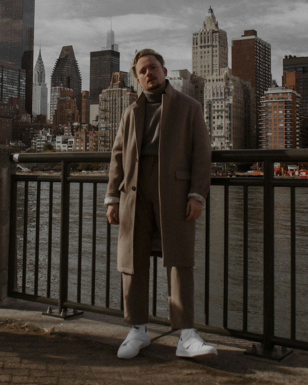 a man standing on a bridge with a city in the background