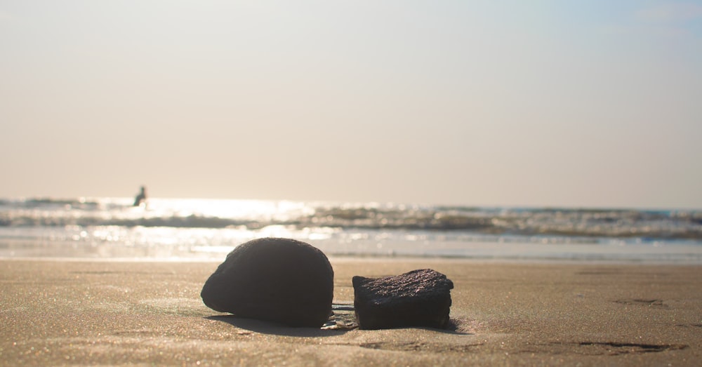 a couple of rocks sitting on top of a sandy beach