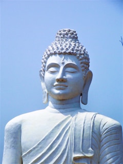 a white buddha statue with a blue sky in the background