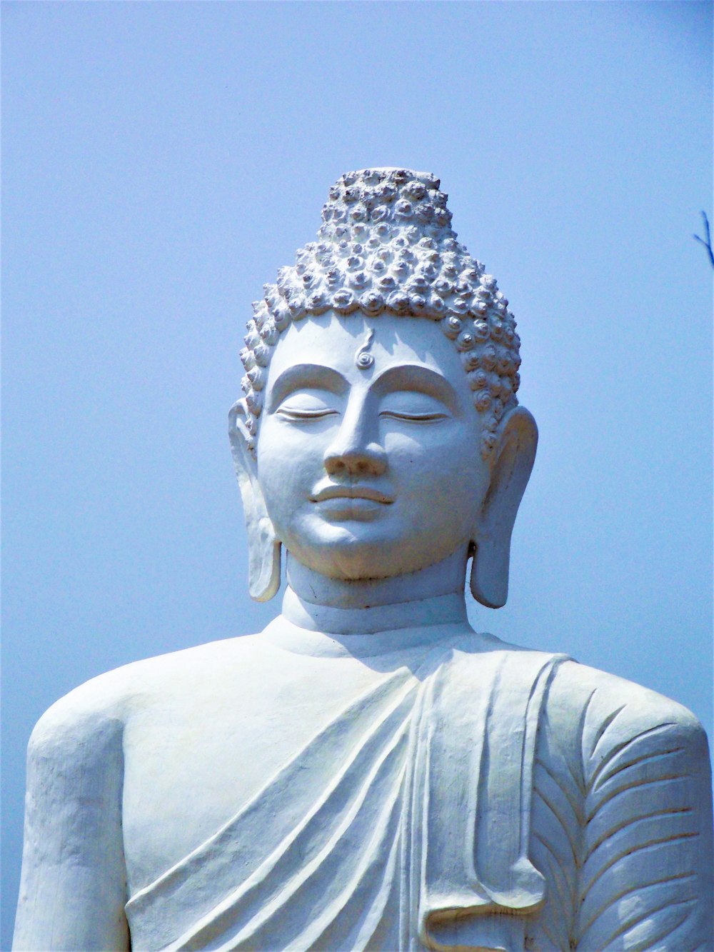 a white buddha statue with a blue sky in the background