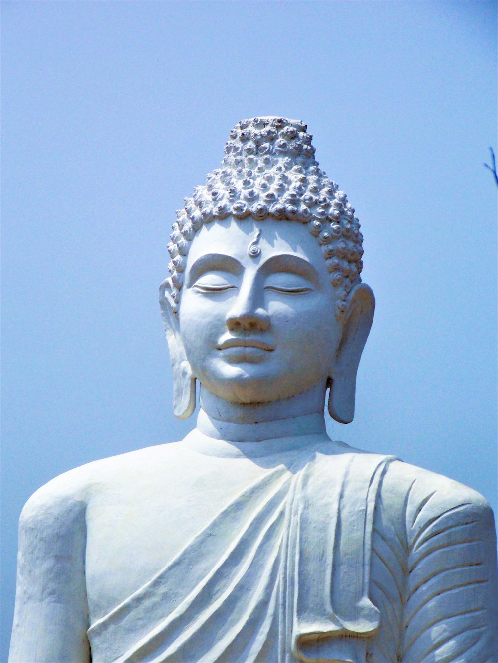 Eine weiße Buddha-Statue mit blauem Himmel im Hintergrund