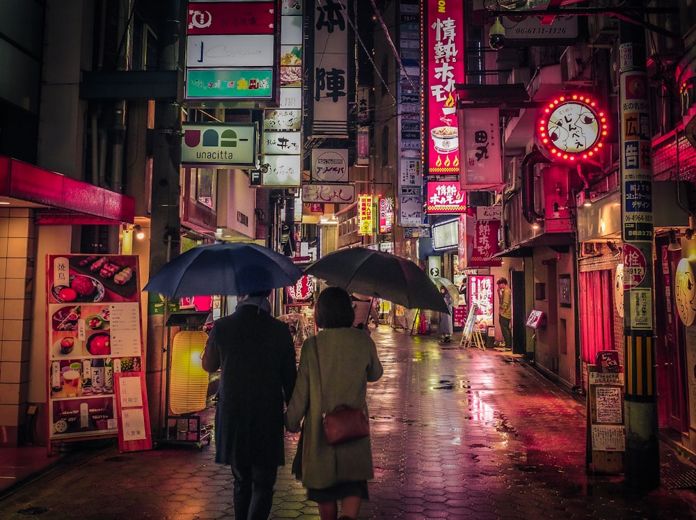 a couple of people walking down a street holding umbrellas