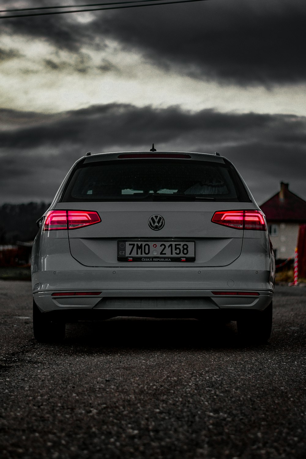 a white car parked in a parking lot under a cloudy sky