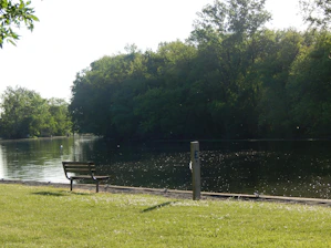 A peaceful view of Tattershall Lakes with a wooden bench overlooking calm water at sunset.