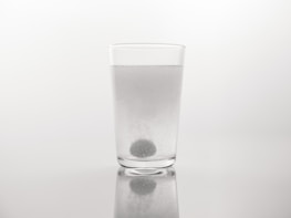 PVA film dissolving in a clear glass of water, illustrating its water-soluble property.