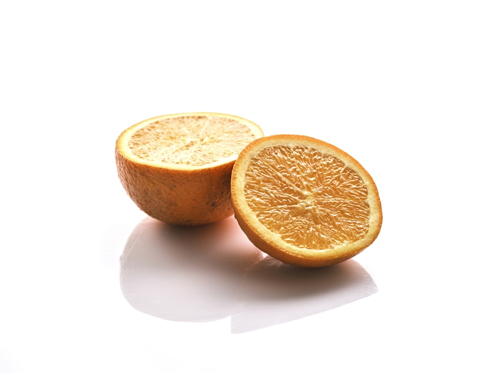 um corte laranja ao meio em uma superfície branca