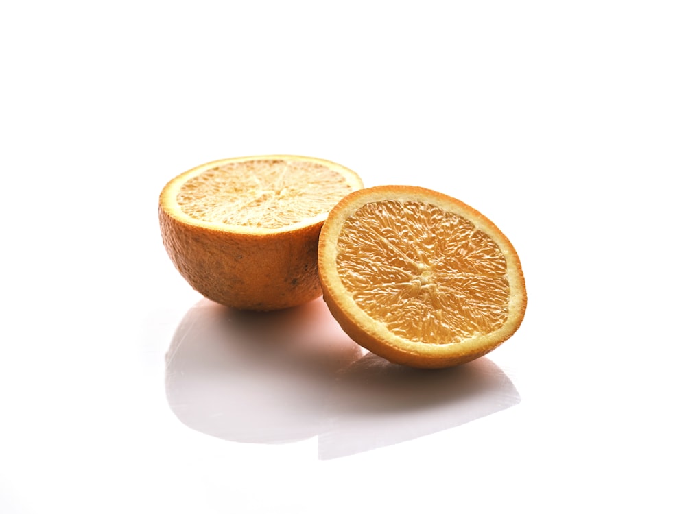 an orange cut in half on a white surface