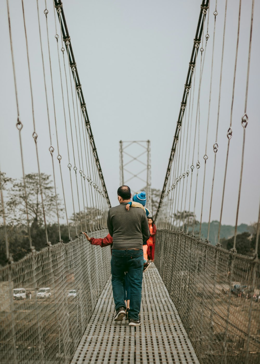 a group of people walking across a suspension bridge