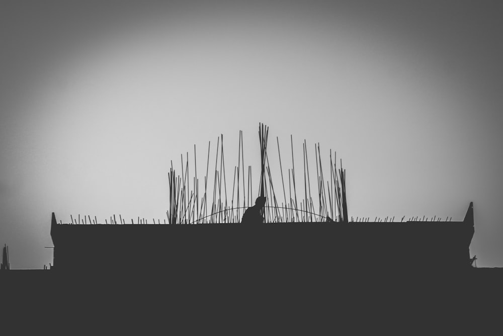 a black and white photo of a person sitting on a roof