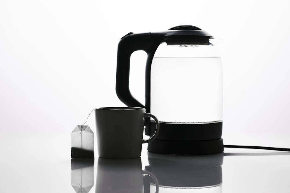 a black and white photo of a kettle and a cup