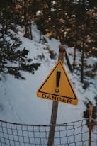 a warning sign on a fence post in the snow