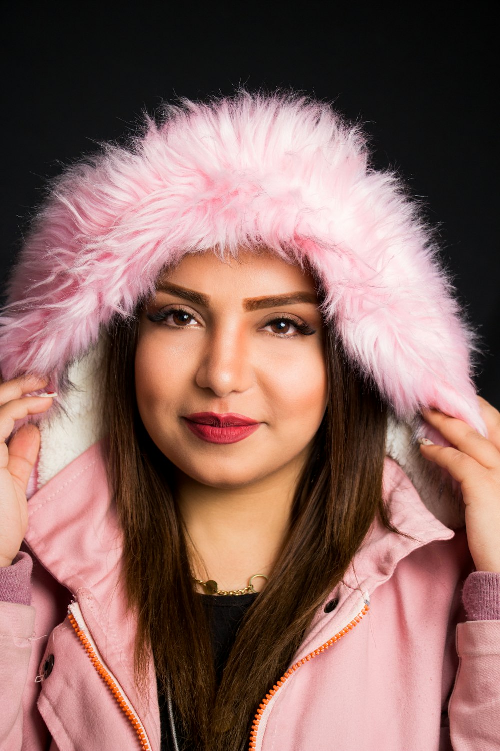 a woman wearing a pink jacket and a furry hat