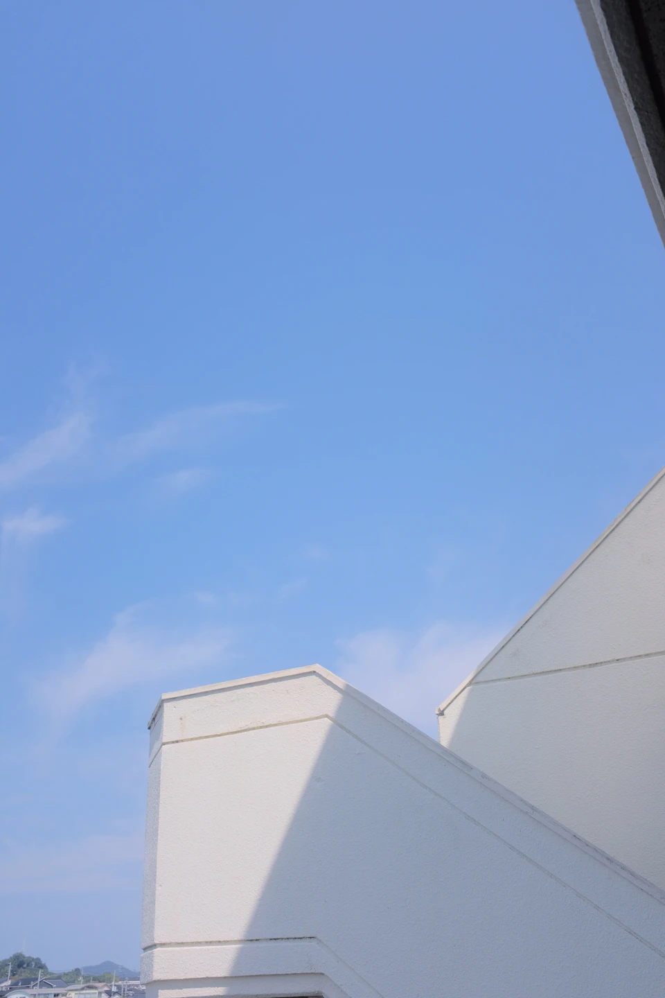 White building with curved roof on hillside overlooks cityscape from a low vantage point