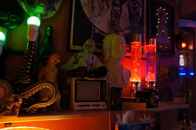 Close-up of colorful 1970s-style decor items including lava lamps and patterned cushions.