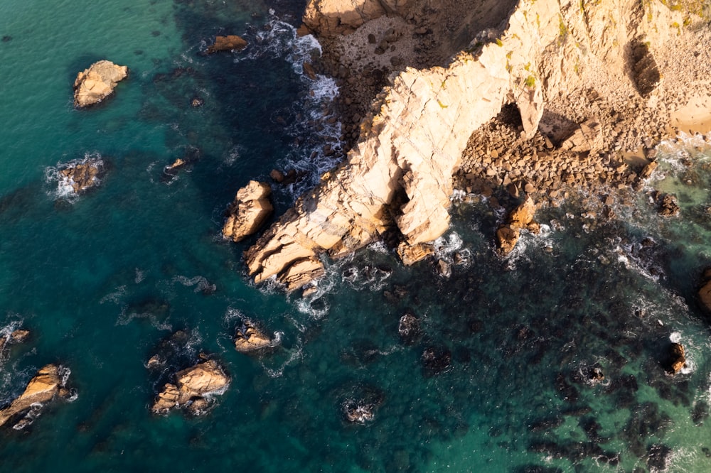 an aerial view of a rocky coastline with blue water