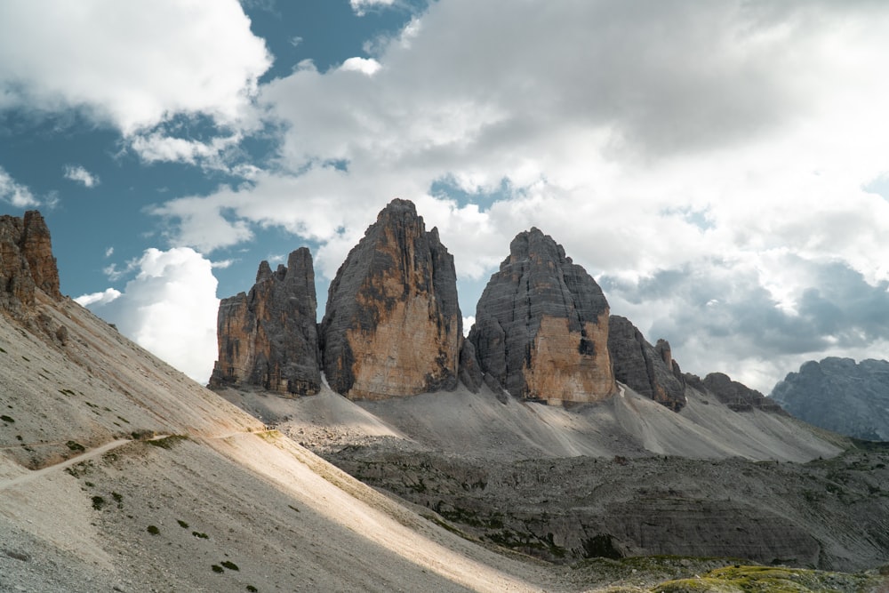 a group of mountains with a cloudy sky in the background