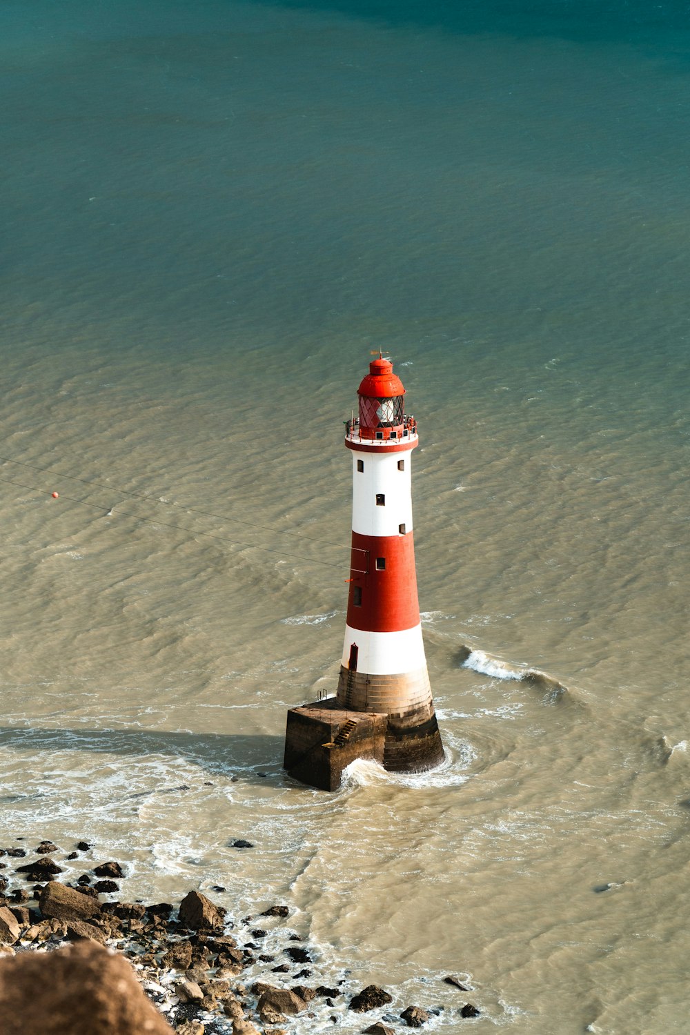 a red and white lighthouse in the middle of the ocean