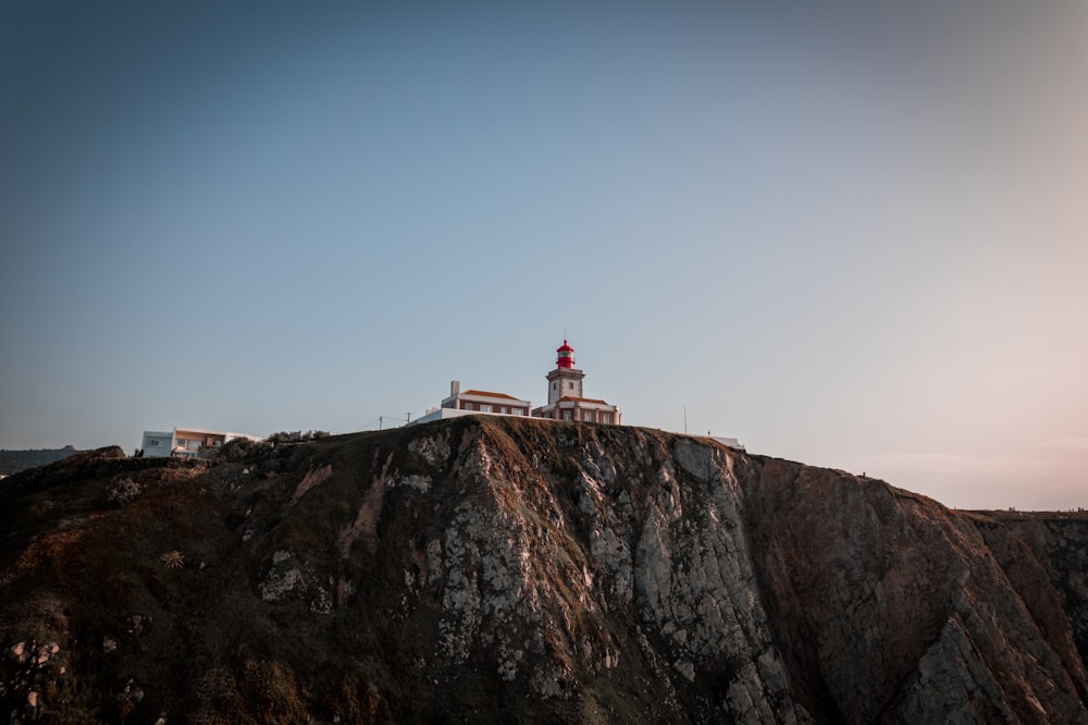 a lighthouse on top of a cliff with a sky background