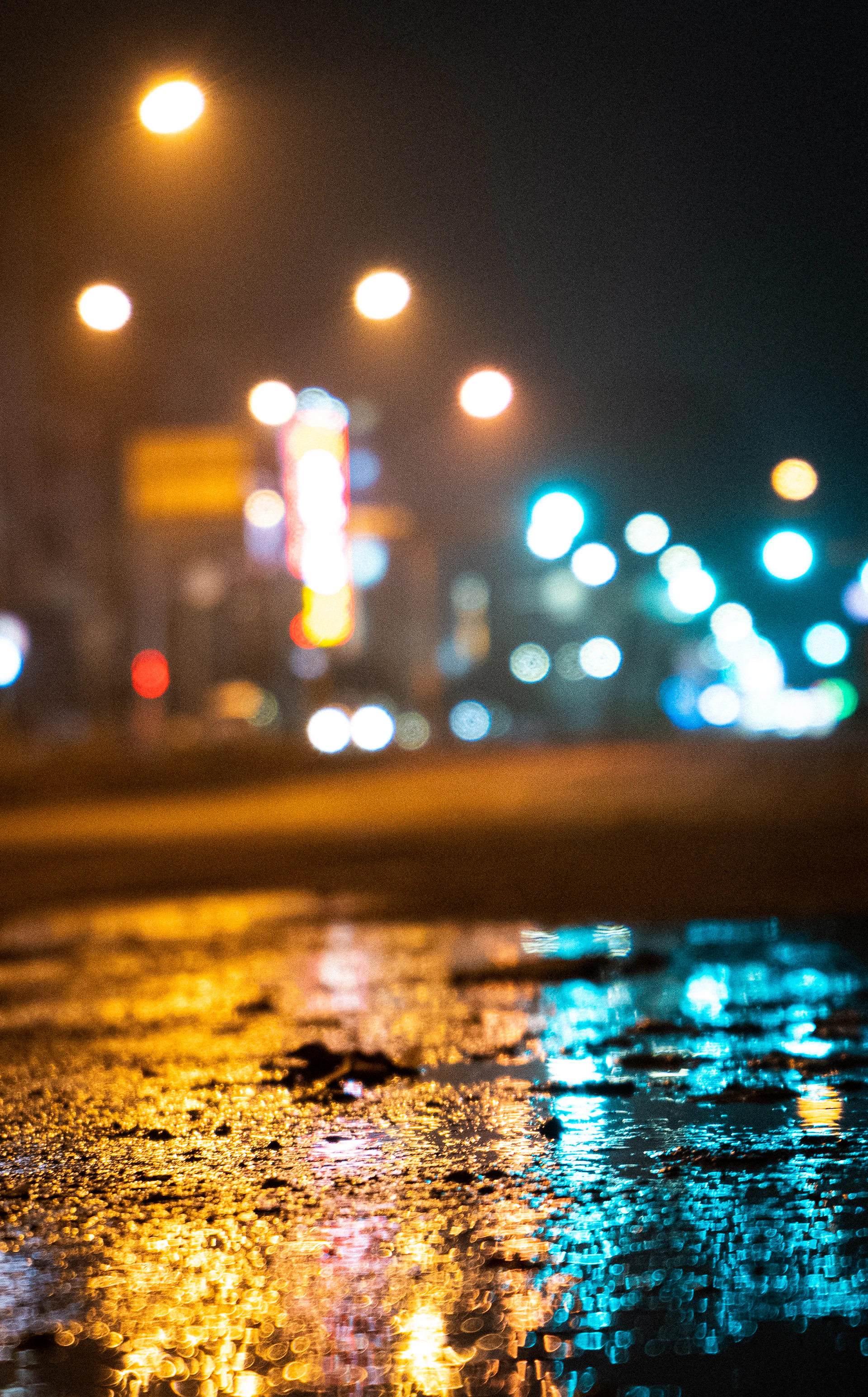a wet street at night with street lights in the background